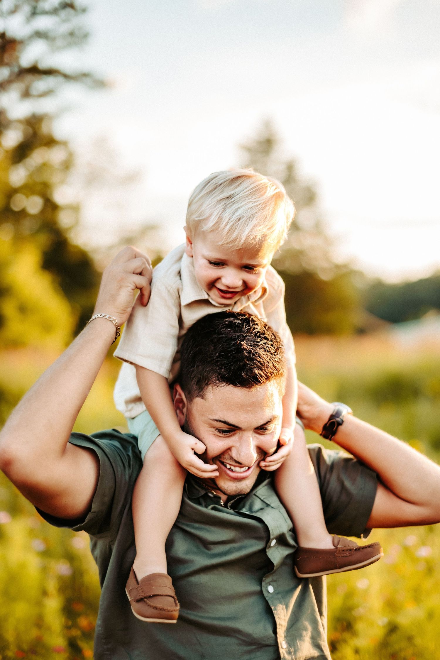 Two people share a joyful moment together outdoors in a sunlit field during golden hour.