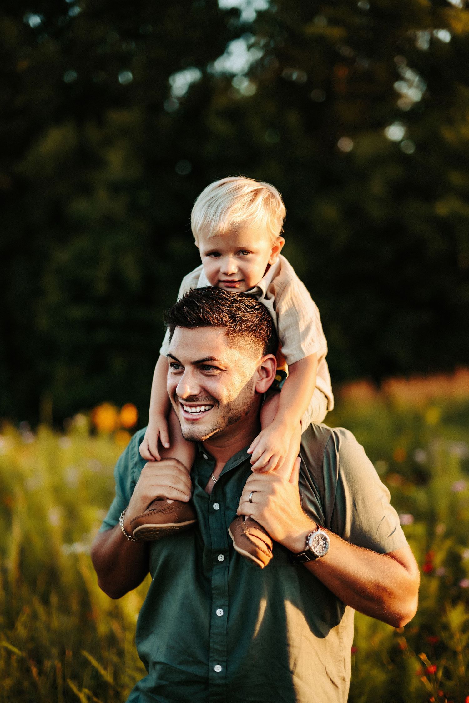A heartwarming outdoor portrait of a father and child enjoying quality time together in a golden field at sunset.