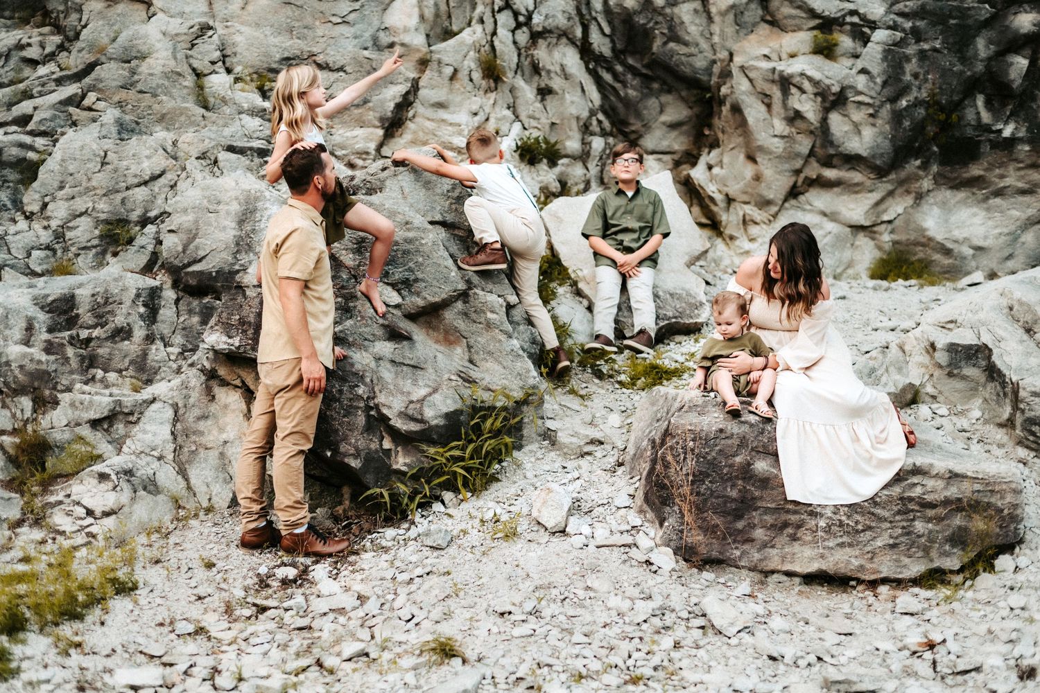 A group of people relax and chat together on rocky terrain during an outdoor adventure.