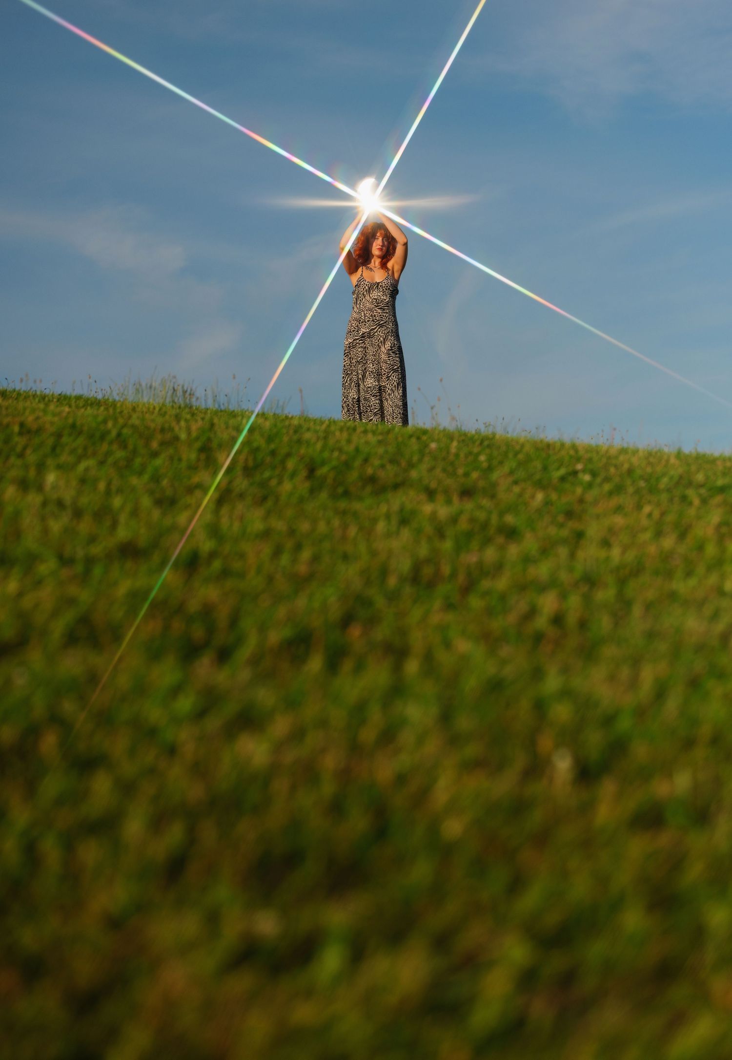 A silhouette stands on a grassy hill with dramatic sunburst effect.