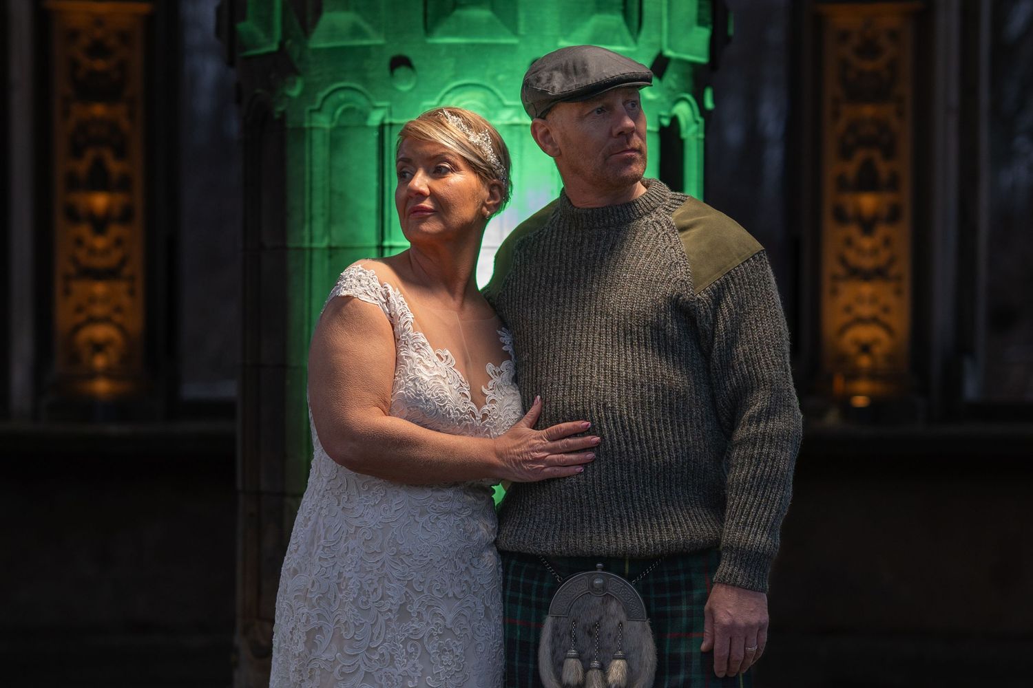 Bride and groom in front of stone pillar lit up green, dalkeith country park, Edinburgh