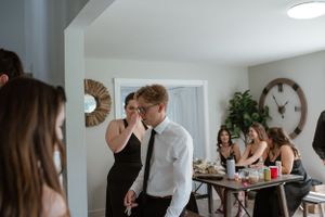 People gather in a home interior with a sunburst mirror and wall clock during a social event.