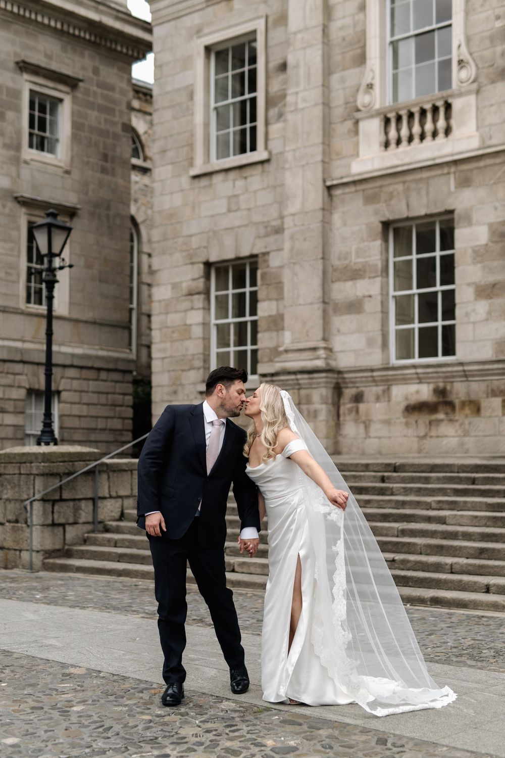 A romantic wedding photo sequence showing a couple in formal attire sharing playful moments on historic stone steps.