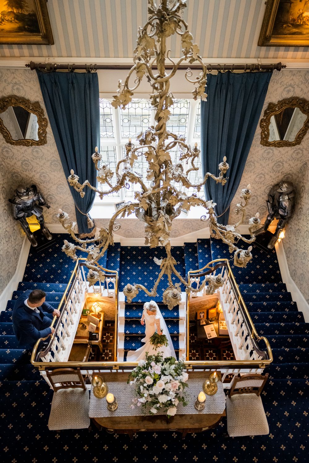 Elegant chandelier-lit wedding venue with blue tufted seating and ornate decor captured from multiple overhead angles.