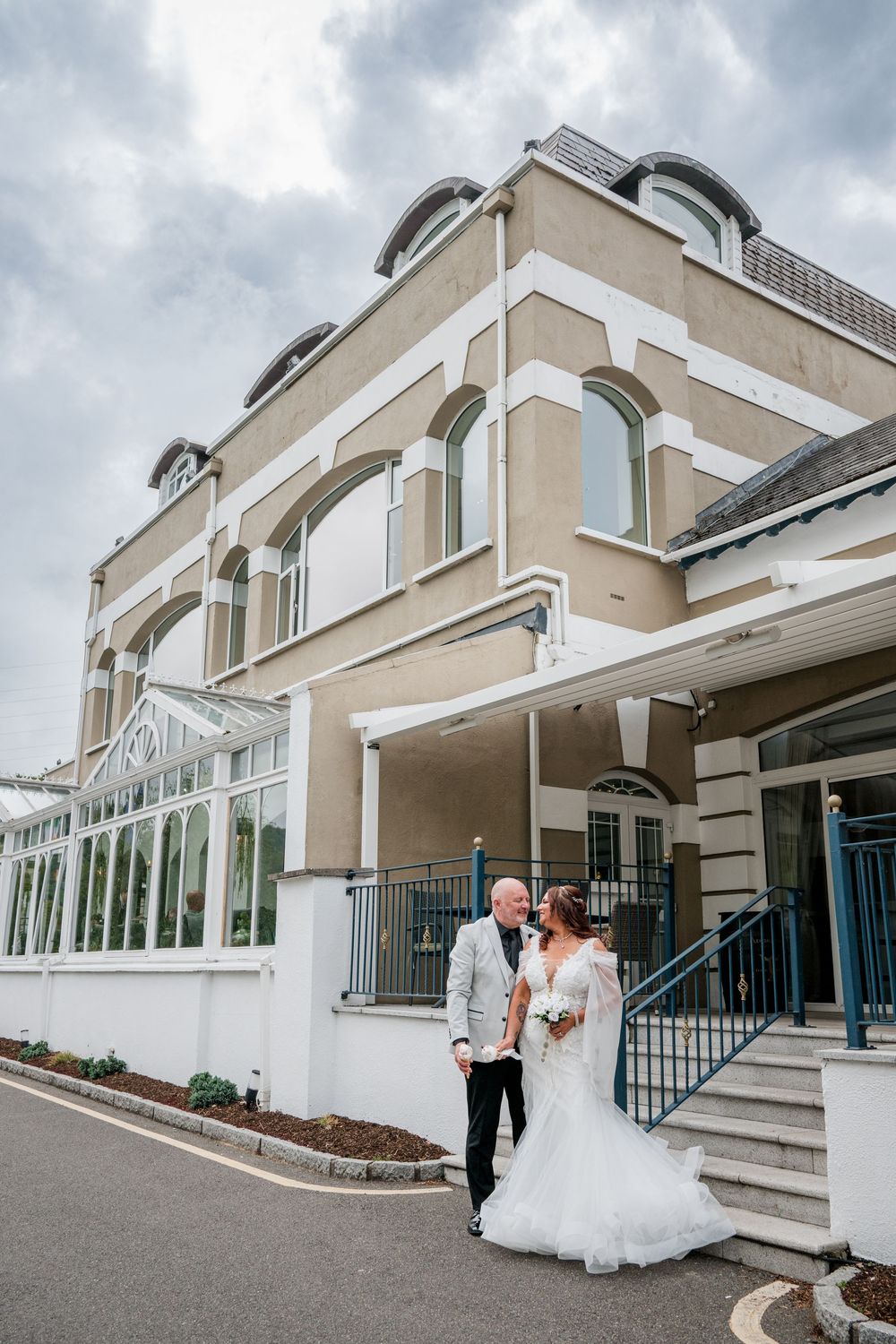 Elegant wedding venue exterior with modern architectural details and glass windows under an overcast sky.