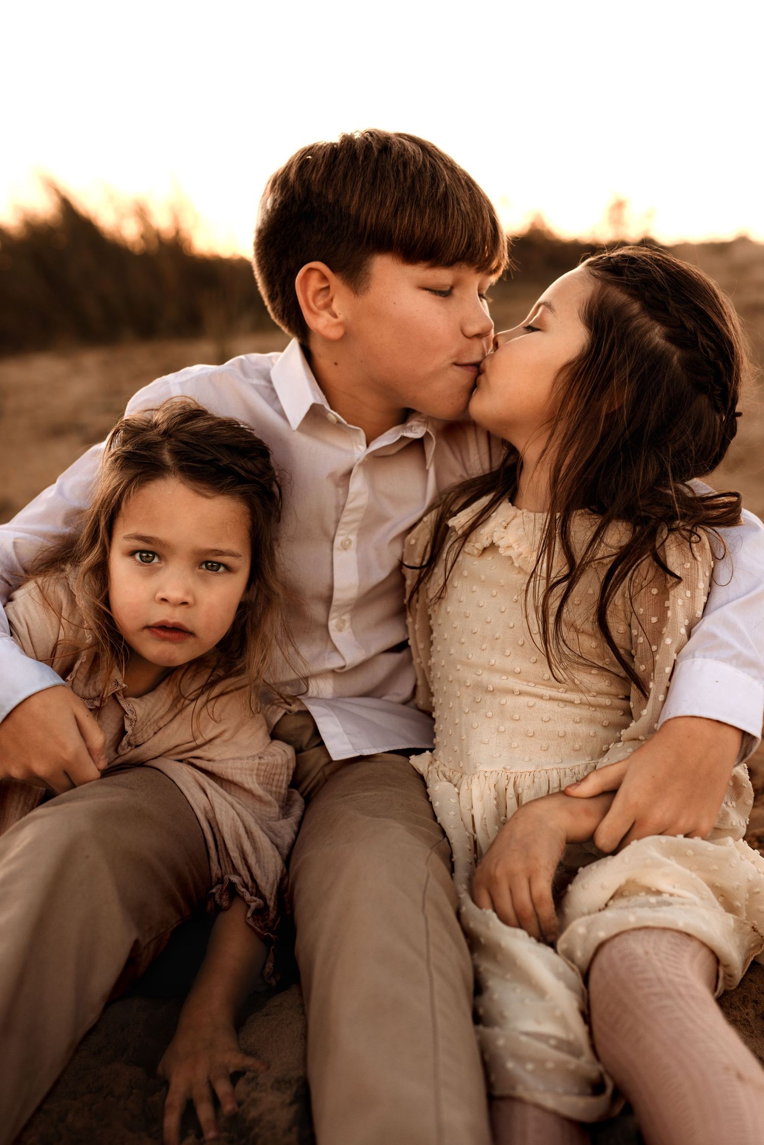 Sweet family photo of children in Javea sharing tender moment together at sunset in warm neutral tones. Javea photographer