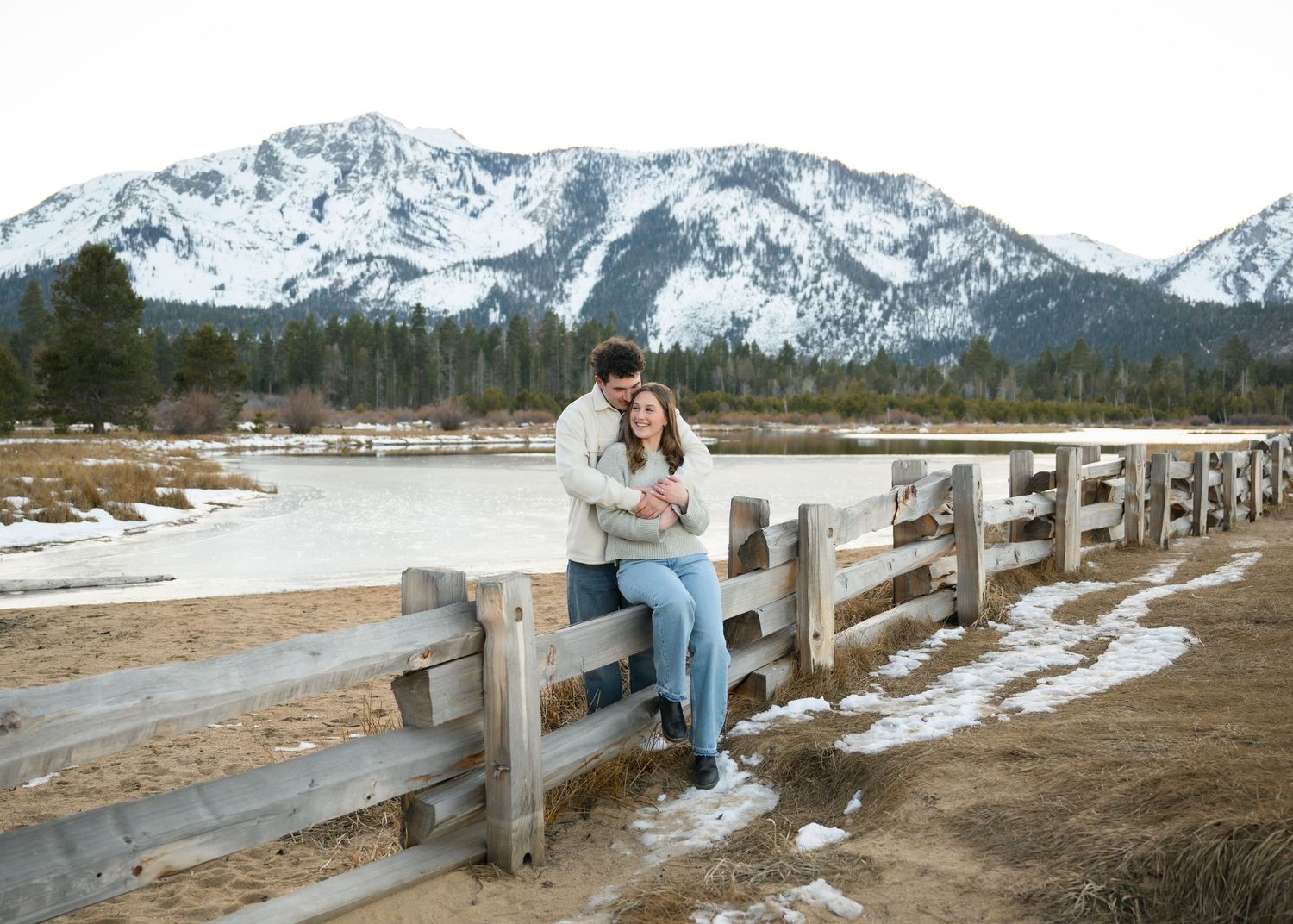 A bride-to-be and a groom-to-be laughing during their engagement session with their wedding photographer among the mountains of Tahoe