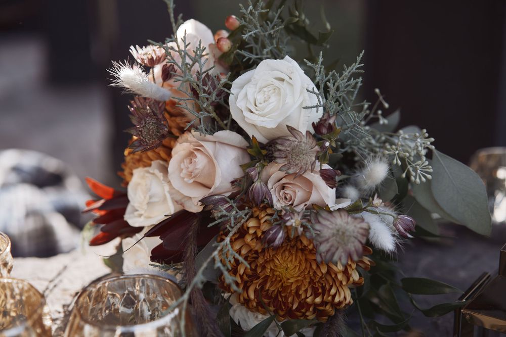 A moody bouquet featuring white roses, brown chrysanthemums, and rustic dried elements in a vintage-inspired arrangement.