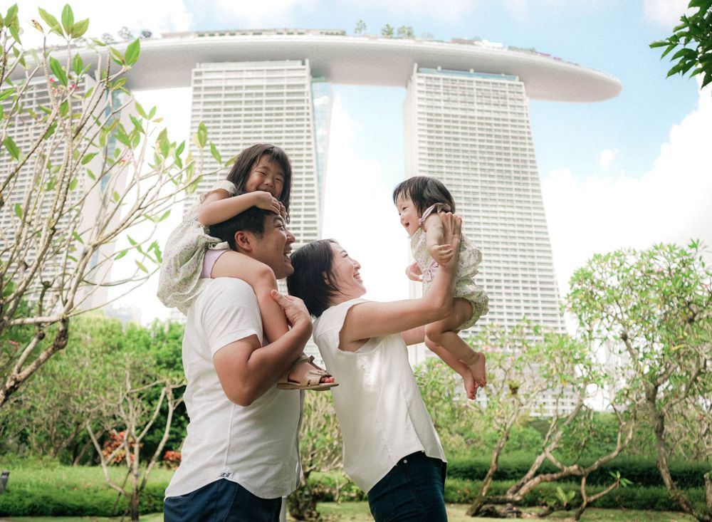 A joyful family plays and lifts children up with Marina Bay Sands in the background.