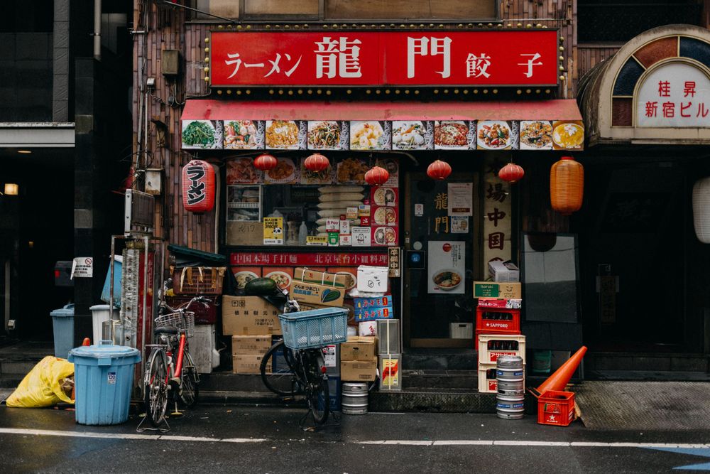 Small traditional Japanese ramen shop storefront with red signage and vending machines.