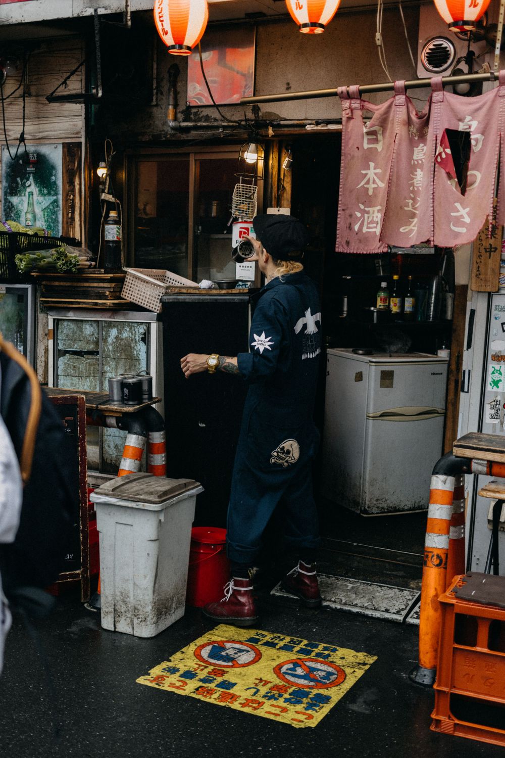 Traditional Japanese izakaya entrance with red lanterns and decorative fabric curtains.