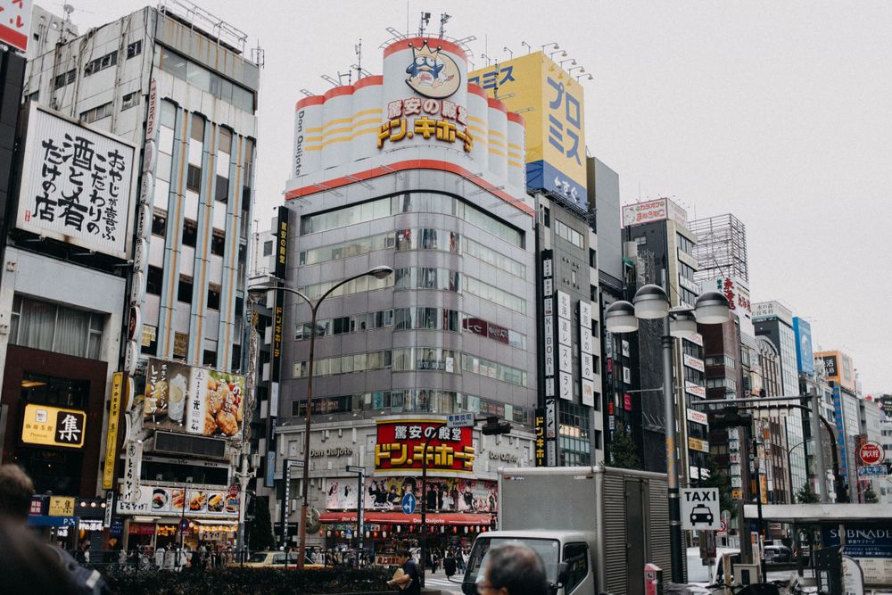 Urban Tokyo cityscape with tall buildings displaying colorful advertising billboards.
