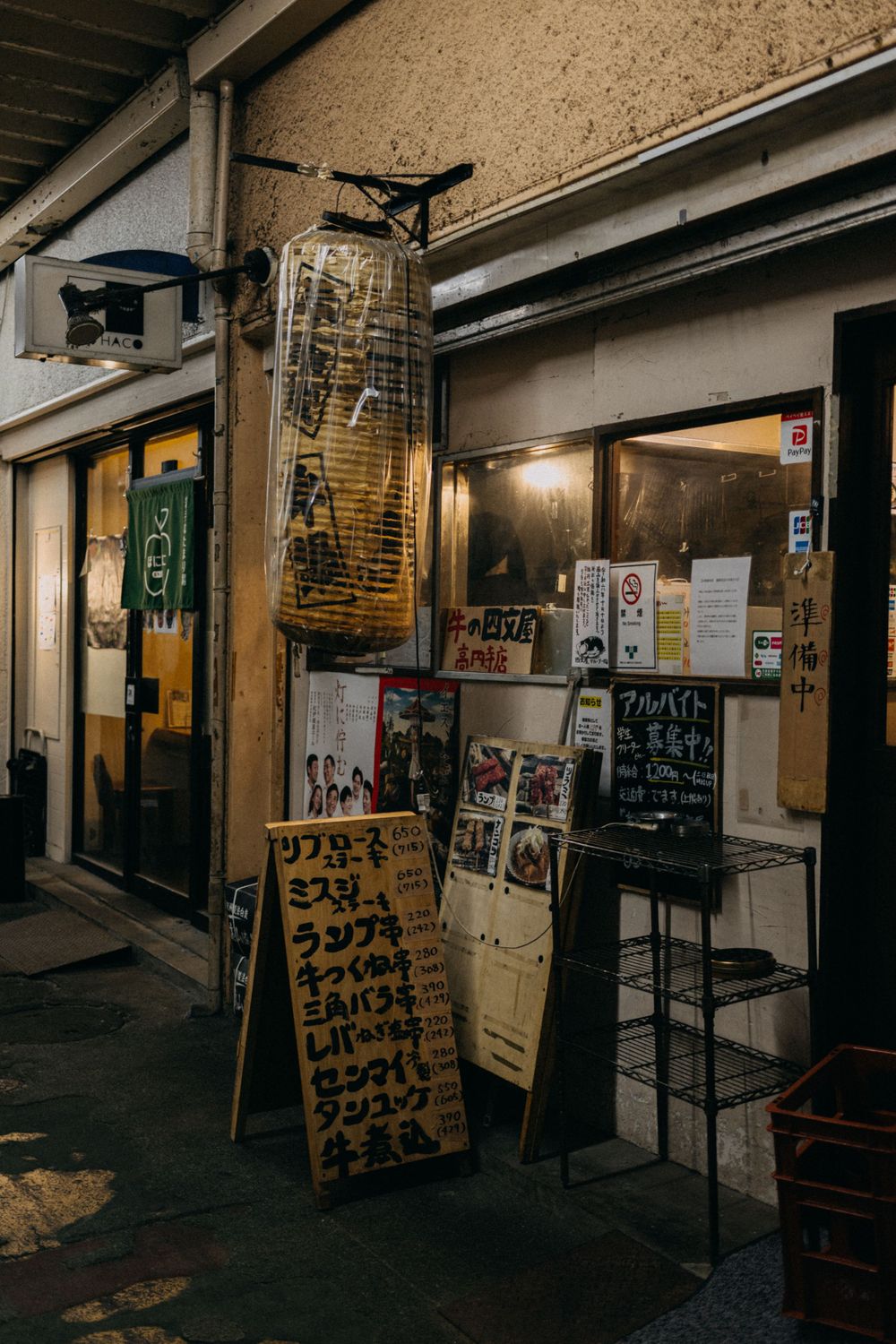 Narrow alley with hanging lanterns and menu boards outside Japanese restaurants.