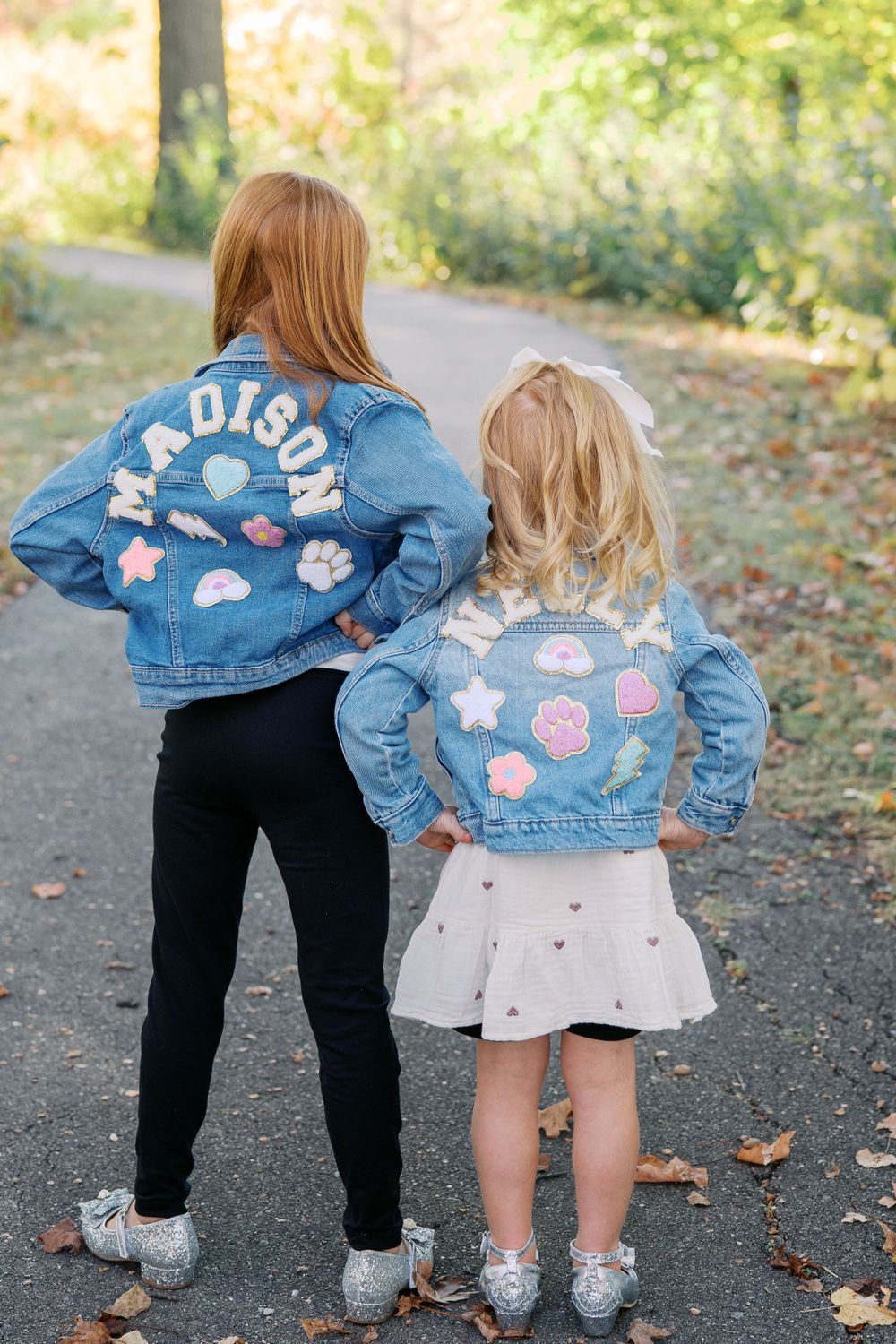 Matching denim jackets with pink and white floral patches shown from behind.
