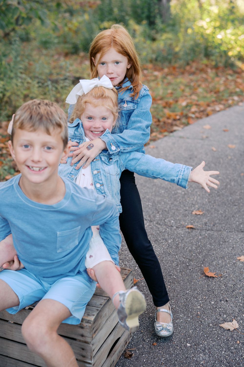 Playful siblings having fun on wooden crates during outdoor photo session.