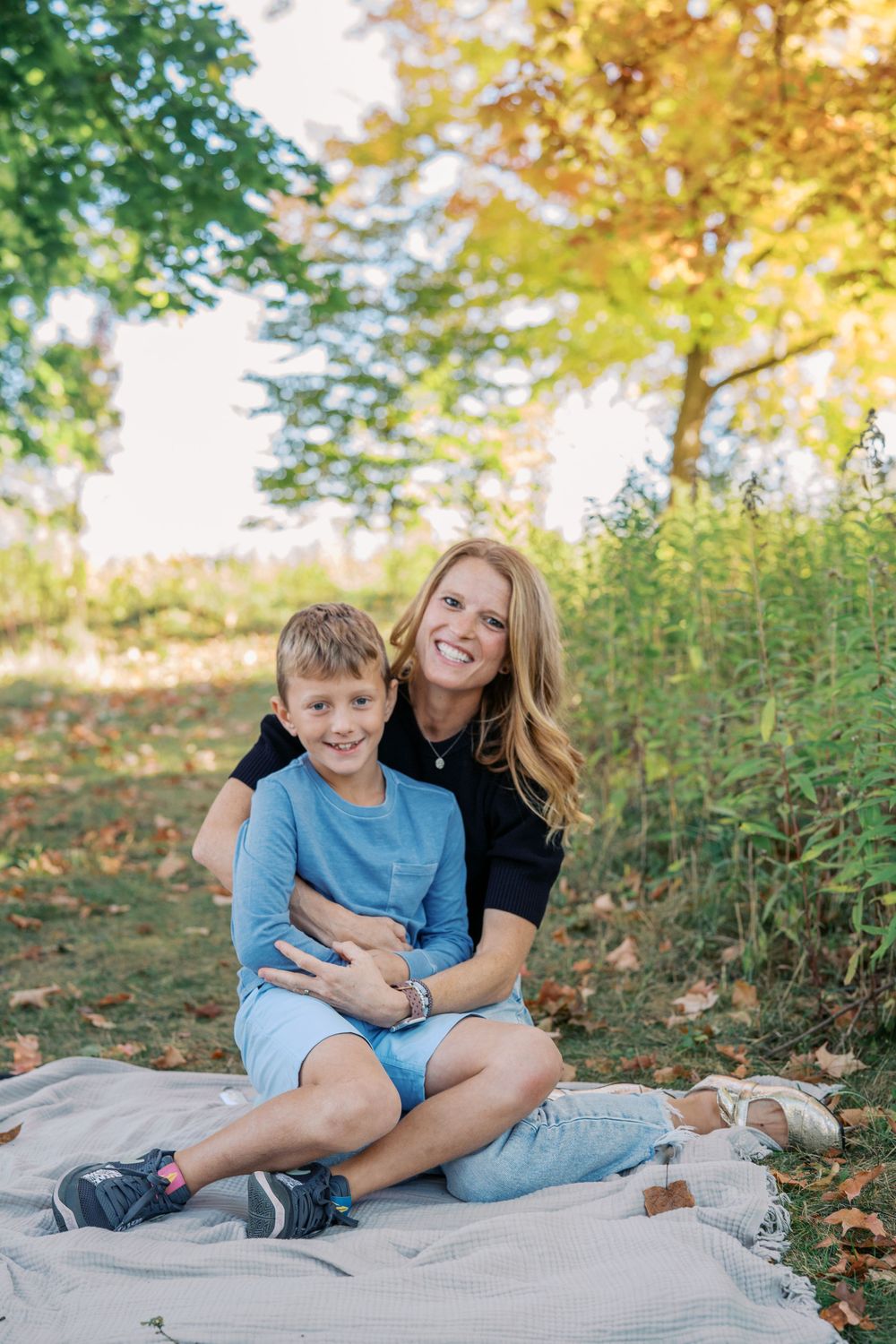 Candid outdoor family photos on a blanket with autumn foliage in the background.