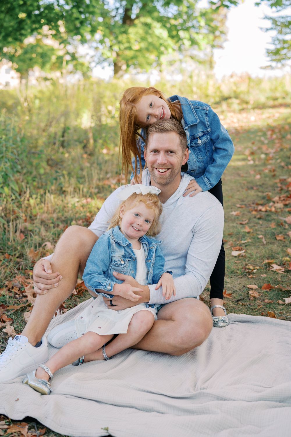 Family members share joyful moments while lounging on a blanket during outdoor photoshoot.