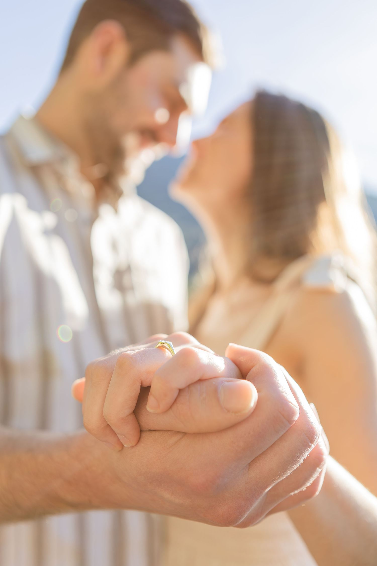 Close-up view of two hands clasped together in an intimate moment with soft natural light in the background.
