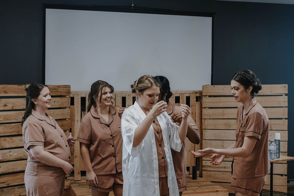 A group in matching blush-colored outfits having a candid moment and laughing together.