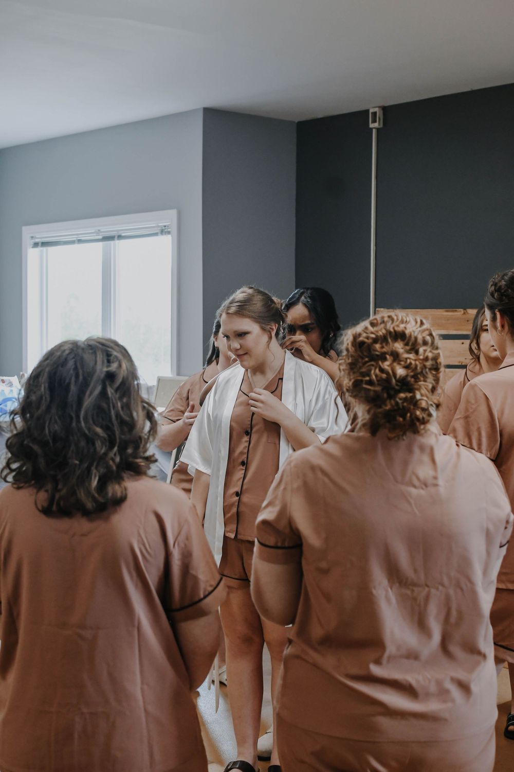 A candid moment shows a small group gathered in a room with gray walls and white decor wearing matching outfits.