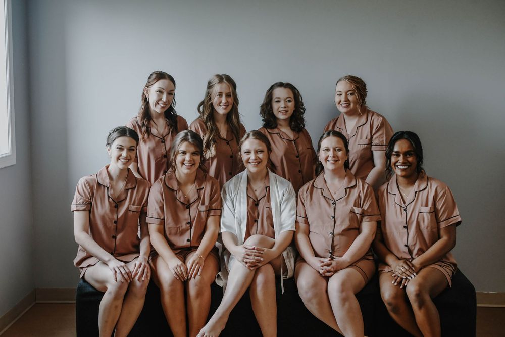Group photo of people wearing matching light brown and beige toned button-up outfits sitting together on a couch.