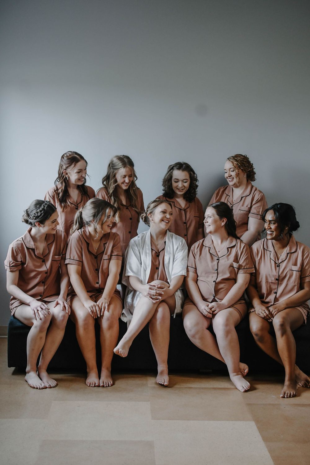 A group wearing coordinated blush-colored outfits sitting together and sharing a joyful moment.