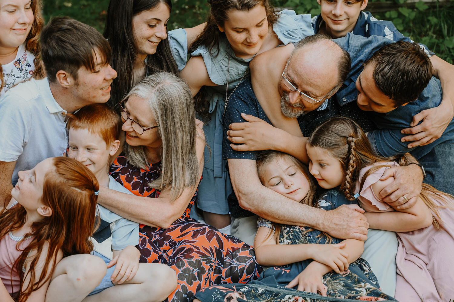 Group of people snuggled together in an intimate family embrace outdoors showing warmth and connection.