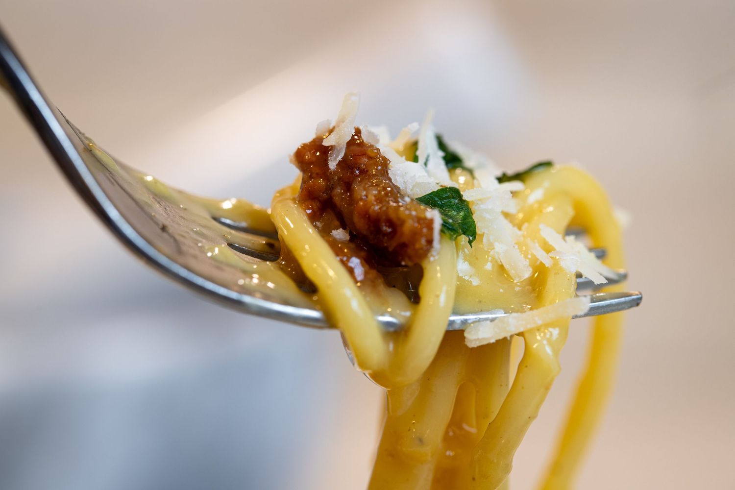 Close-up of carbonara and parmesan cheese on a fork.