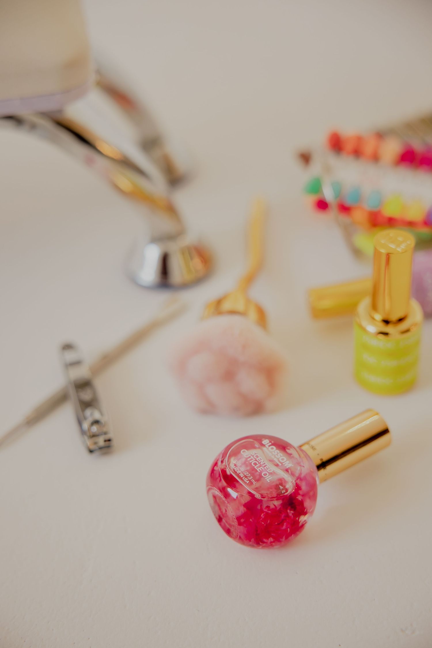 Collection of nail polish bottles and beauty tools scattered on white surface with soft focus.