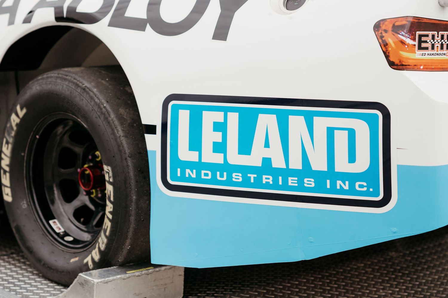 Delivery truck with Leland Industries logo and branding parked in a warehouse loading area.