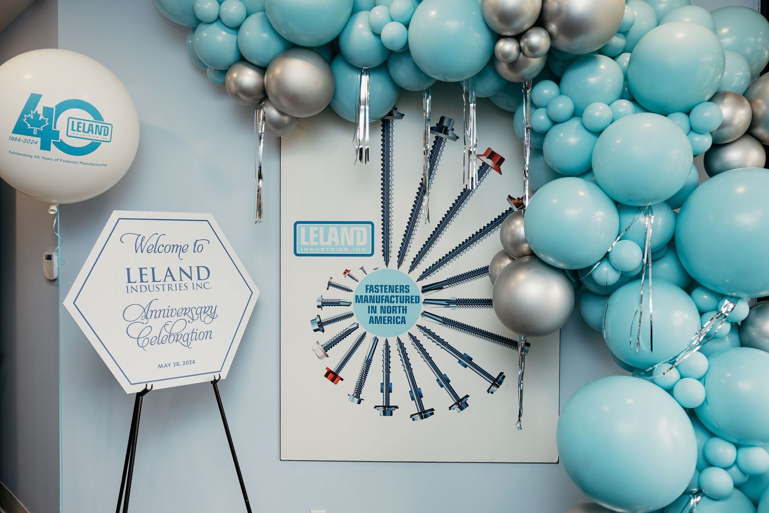 Decorative balloon arch in turquoise and silver colors with event signage.