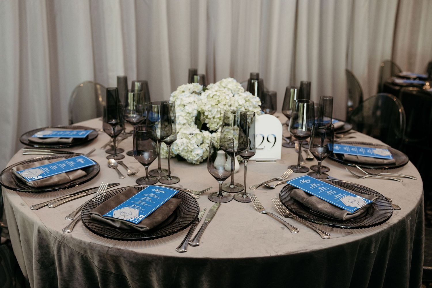 Round dining tables set with formal place settings and blue accents.