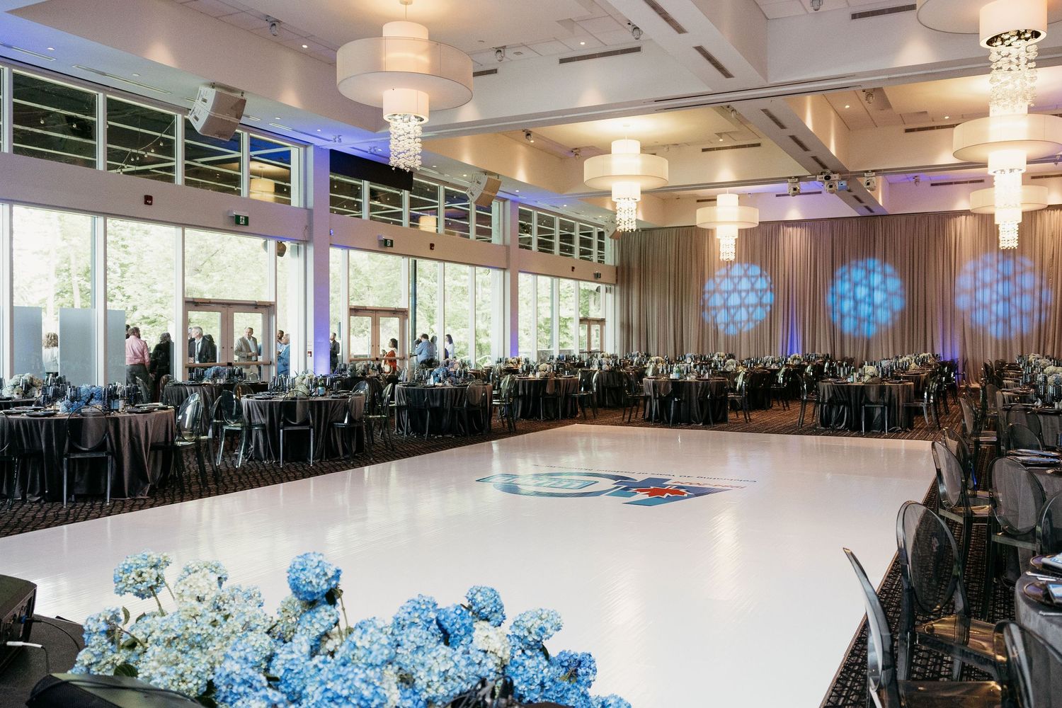 Spacious event venue with white dance floor and blue accent lighting for corporate celebration.