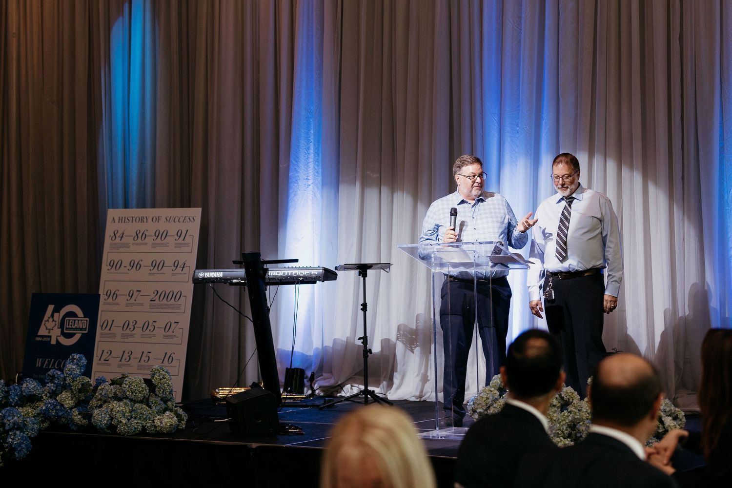 Stage setup with professional lighting and white curtain backdrop for corporate presentation.
