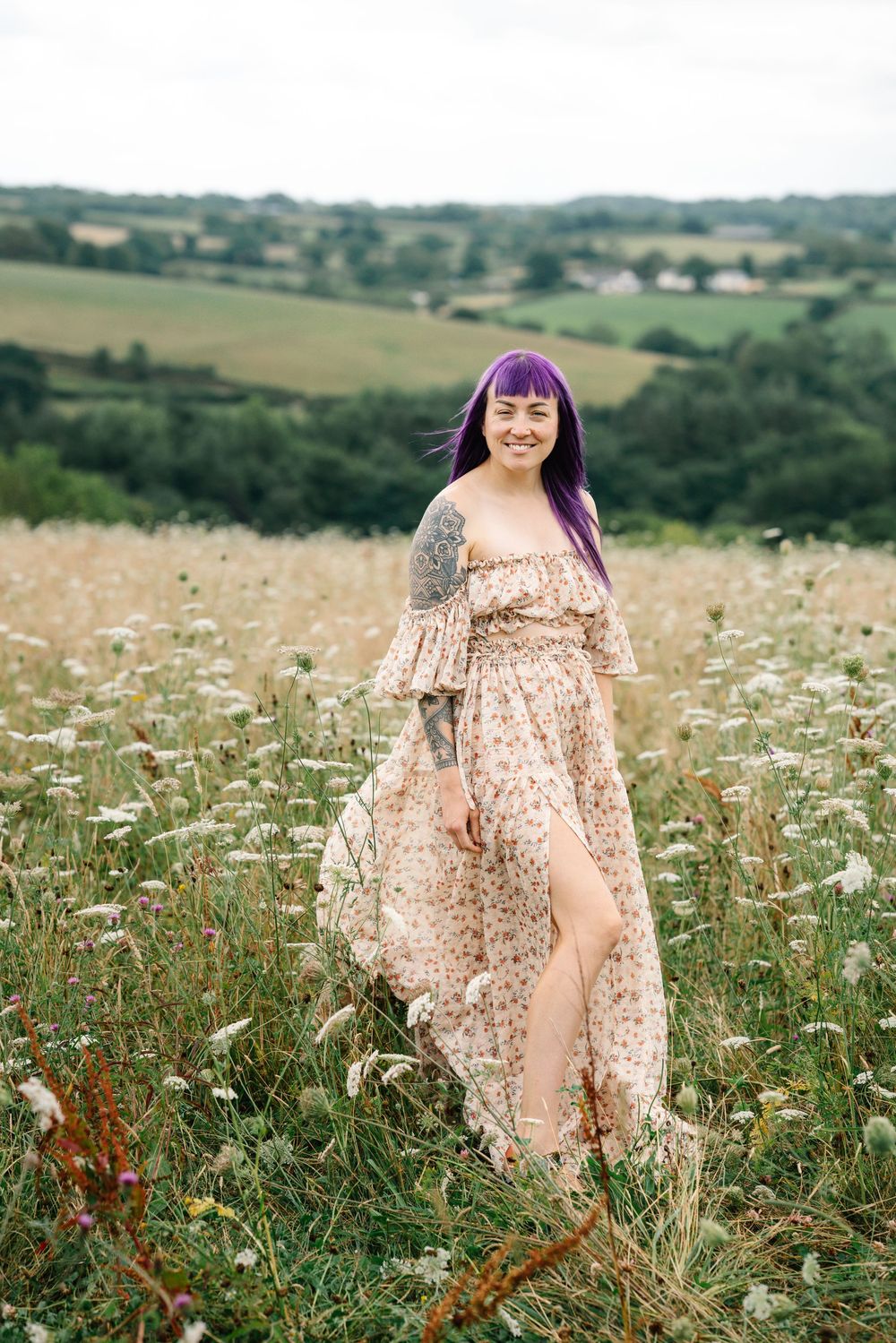A flowy floral dress flows in the breeze as someone stands in a wildflower meadow on a sunny summer day.