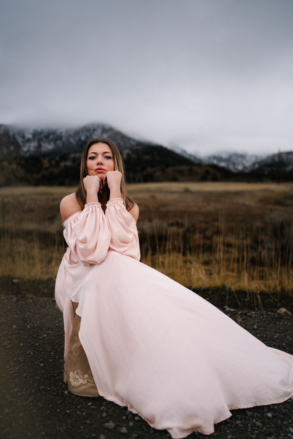 Ethereal pink gown flows in mountain breeze against dramatic winter landscape.