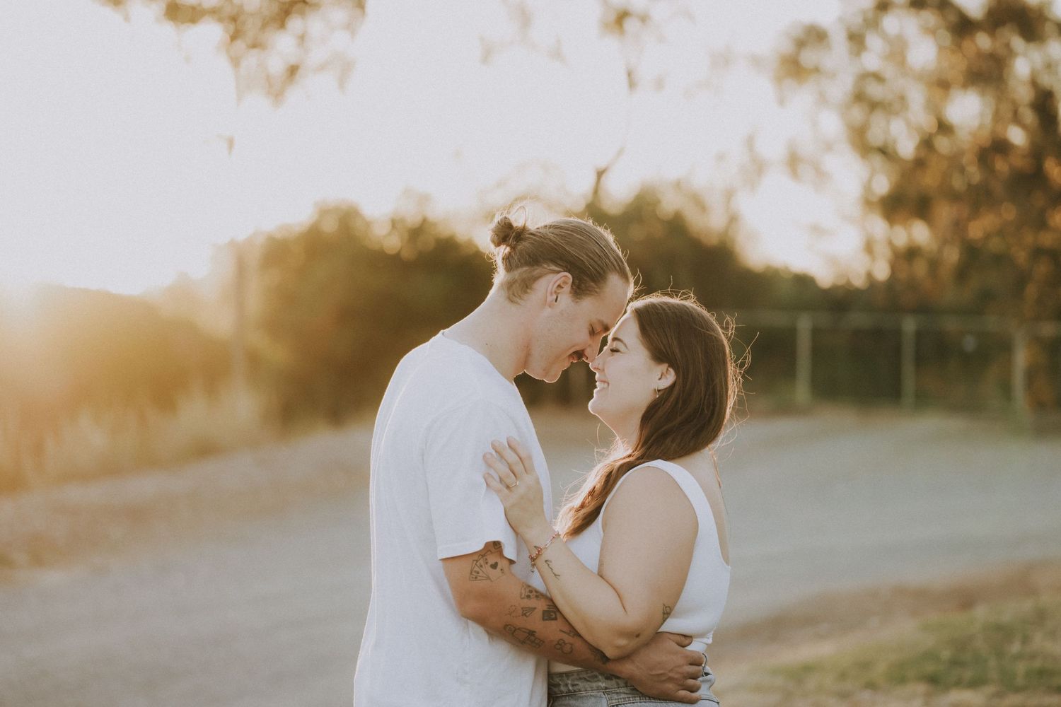 A romantic sunset embrace between a couple on a rural path surrounded by golden light.