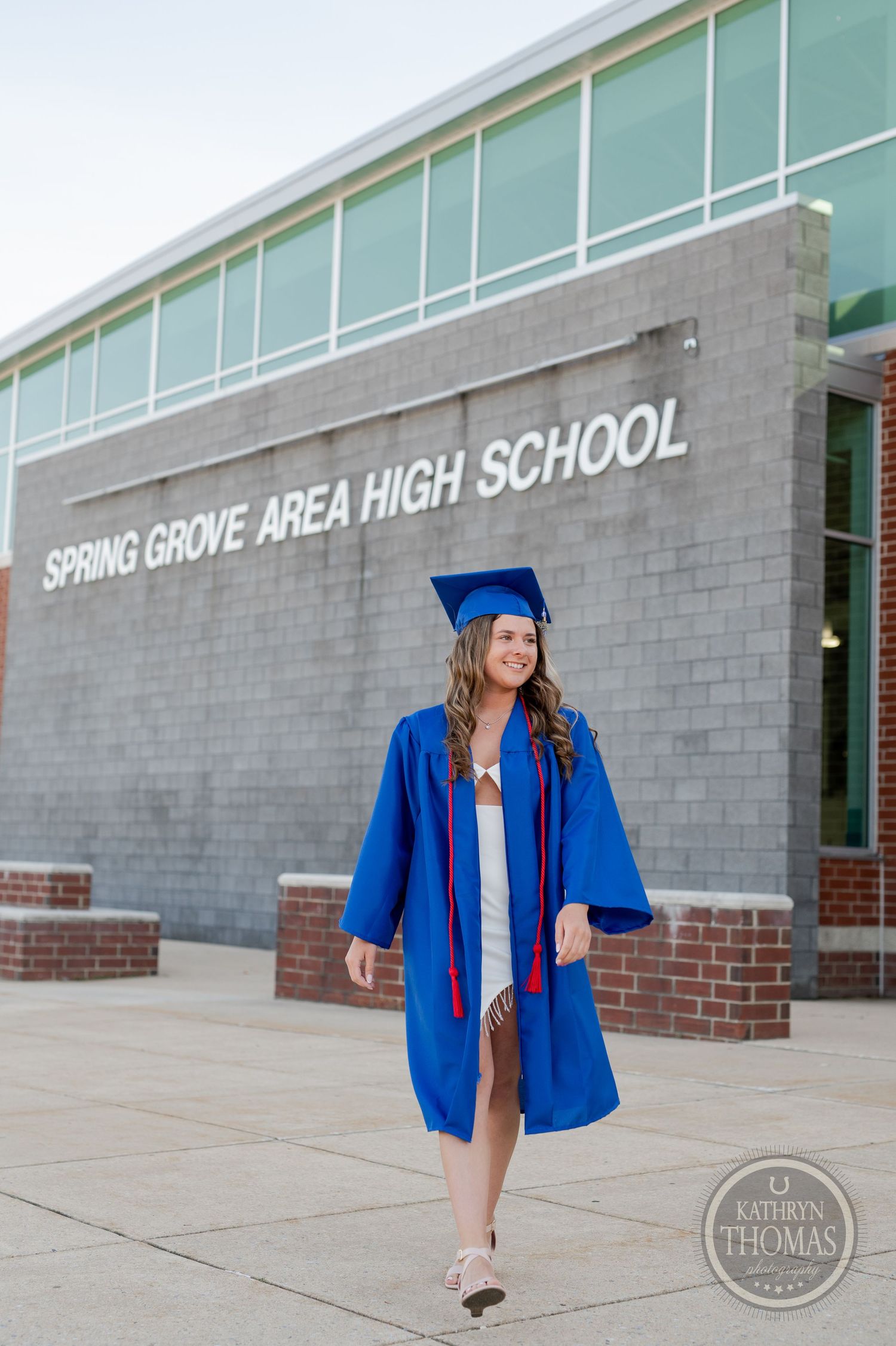 Graduation photo of someone walking in blue regalia outside Spring Grove Area High School.