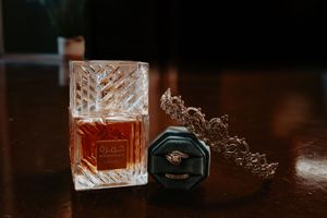 Crystal perfume bottle reflecting amber light next to dark wedding stationery.