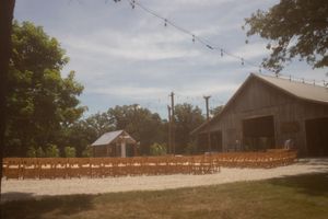 String lights hang between rustic barn buildings under a blue sky.