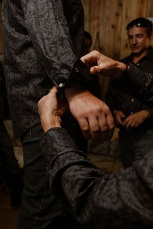 Close-up details of hands and clothing in dim lighting at an event.