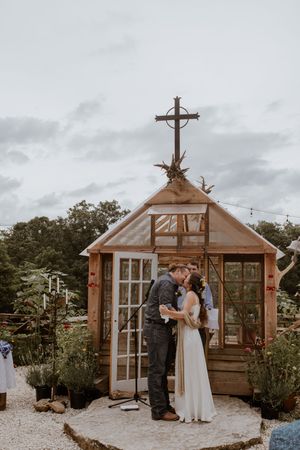 Rustic wooden greenhouse chapel decorated for an intimate outdoor wedding ceremony.
