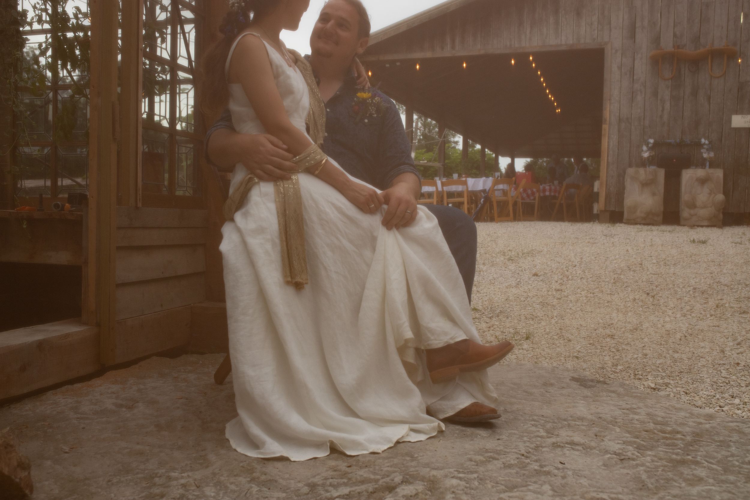 A couple dances together outdoors at a rustic venue celebration.