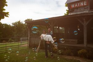 Rustic wooden building with 'Wayne' sign and floating bubbles in sunset lighting.