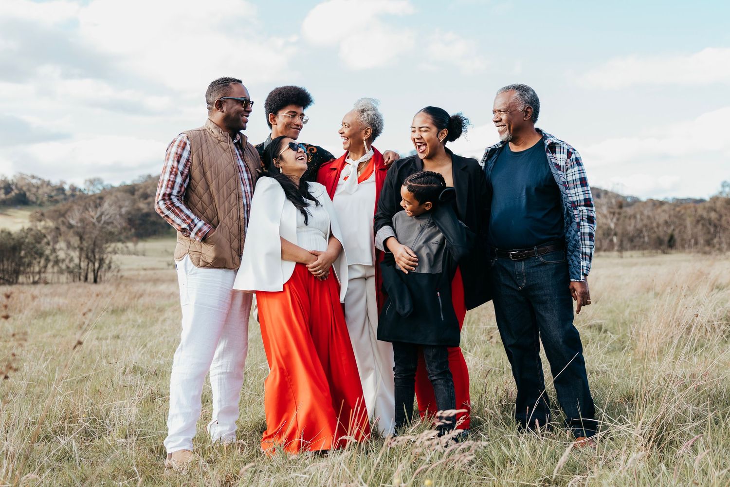 Family portrait in tall golden grass during sunset with warm autumn lighting.