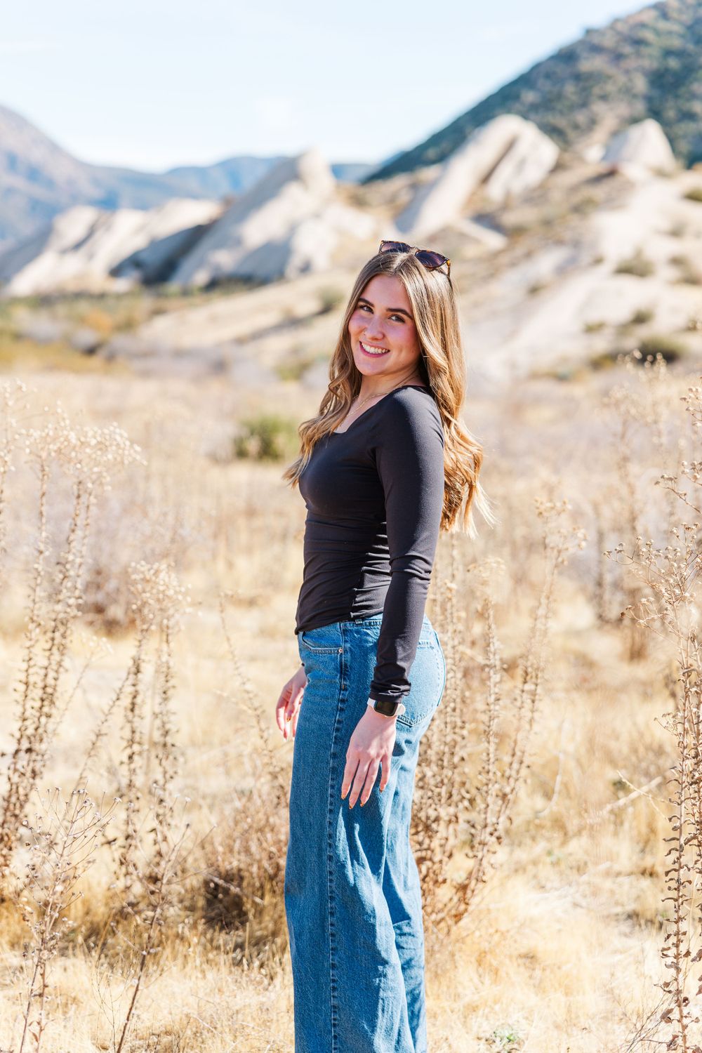 Casual outdoor portrait against scenic mountain backdrop with golden dry grass.