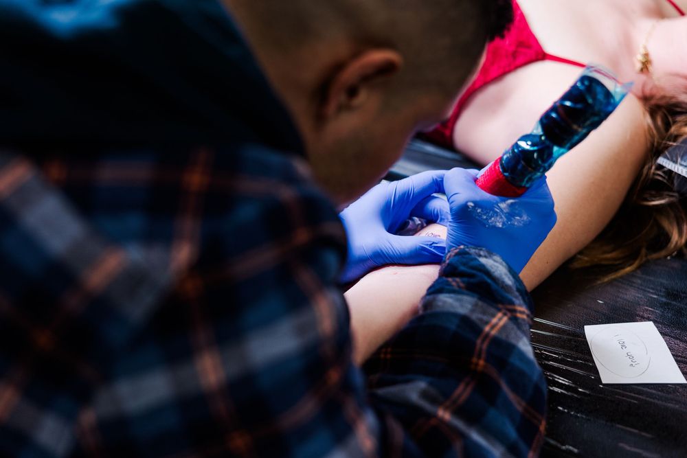 Close-up of tattoo machine in action as artist works on client's arm.