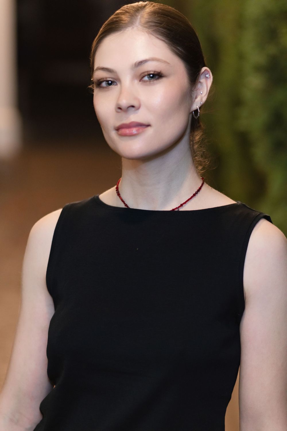 Elegant portrait in black sleeveless dress with hair pulled back.