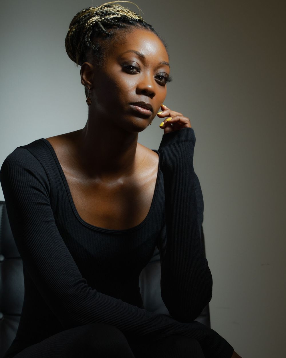 Dramatic portrait of someone in a black sweater with natural lighting and thoughtful expression.