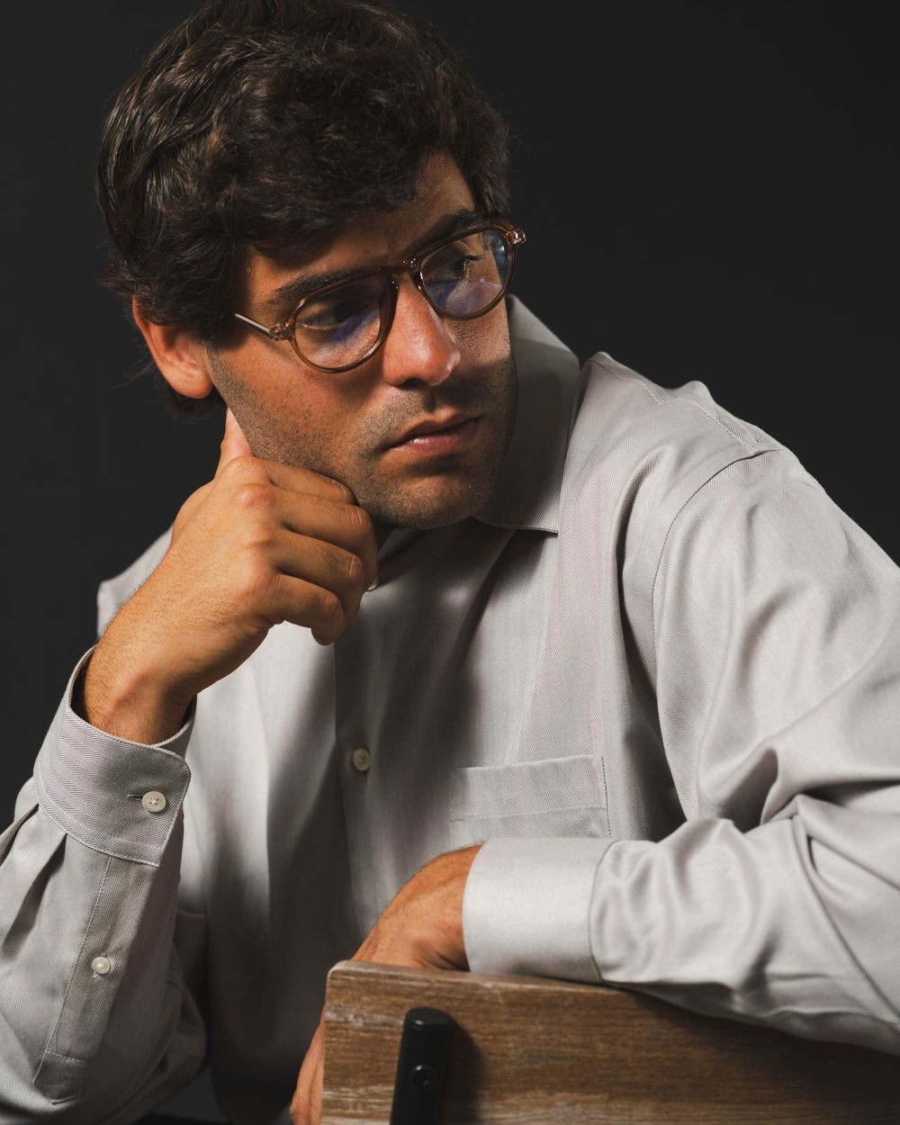 Contemplative studio portrait with glasses and white button-down shirt.